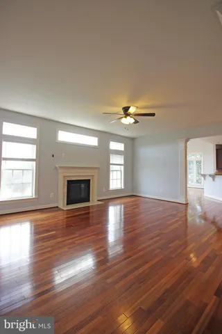 an empty room with wooden floor fireplace and windows