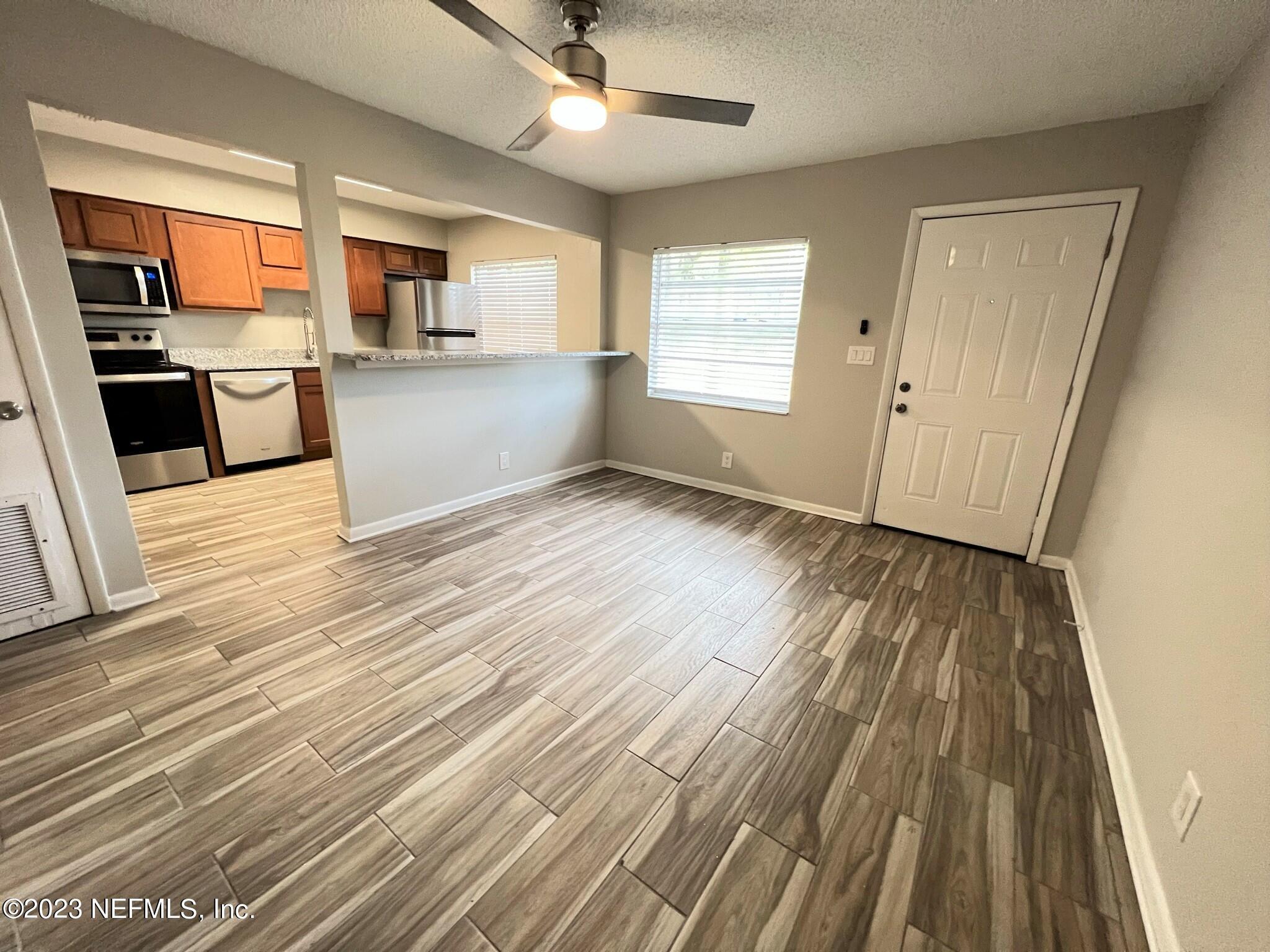 5404 101st Street, Unit 4 Jacksonville, FL 32210 - Photo 2 of 8 an empty room with wooden floor kitchen view and a window