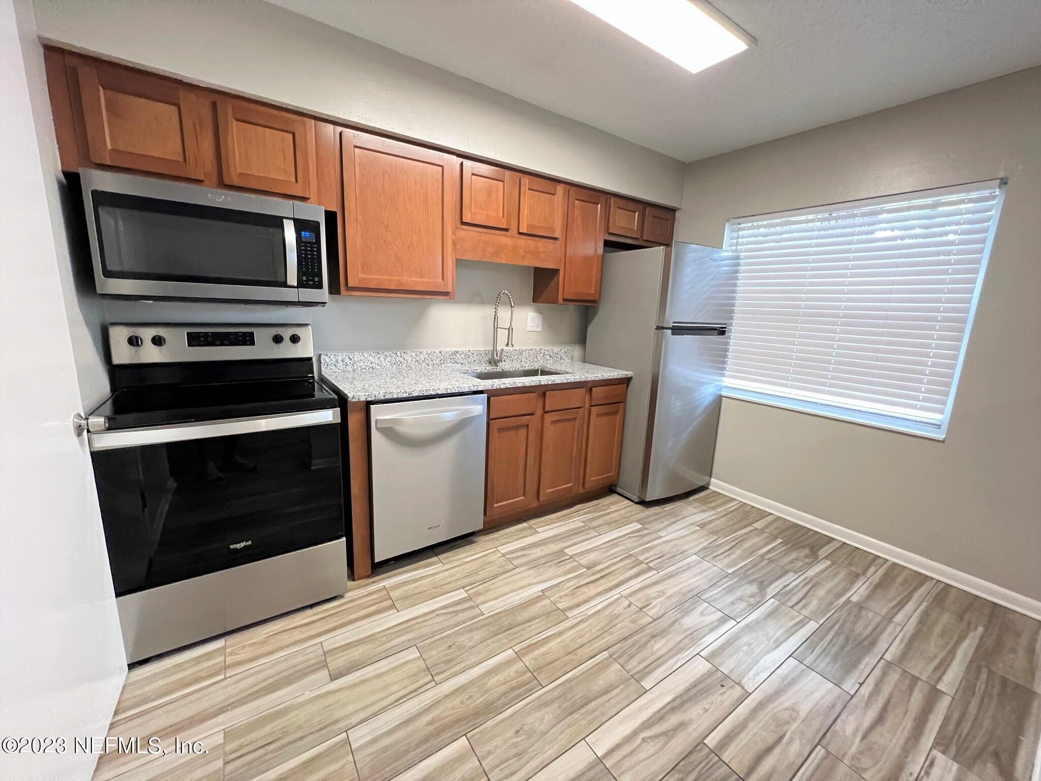 5404 101st Street, Unit 4 Jacksonville, FL 32210 - Photo 4 of 8 a kitchen with stainless steel appliances granite countertop a stove microwave and sink