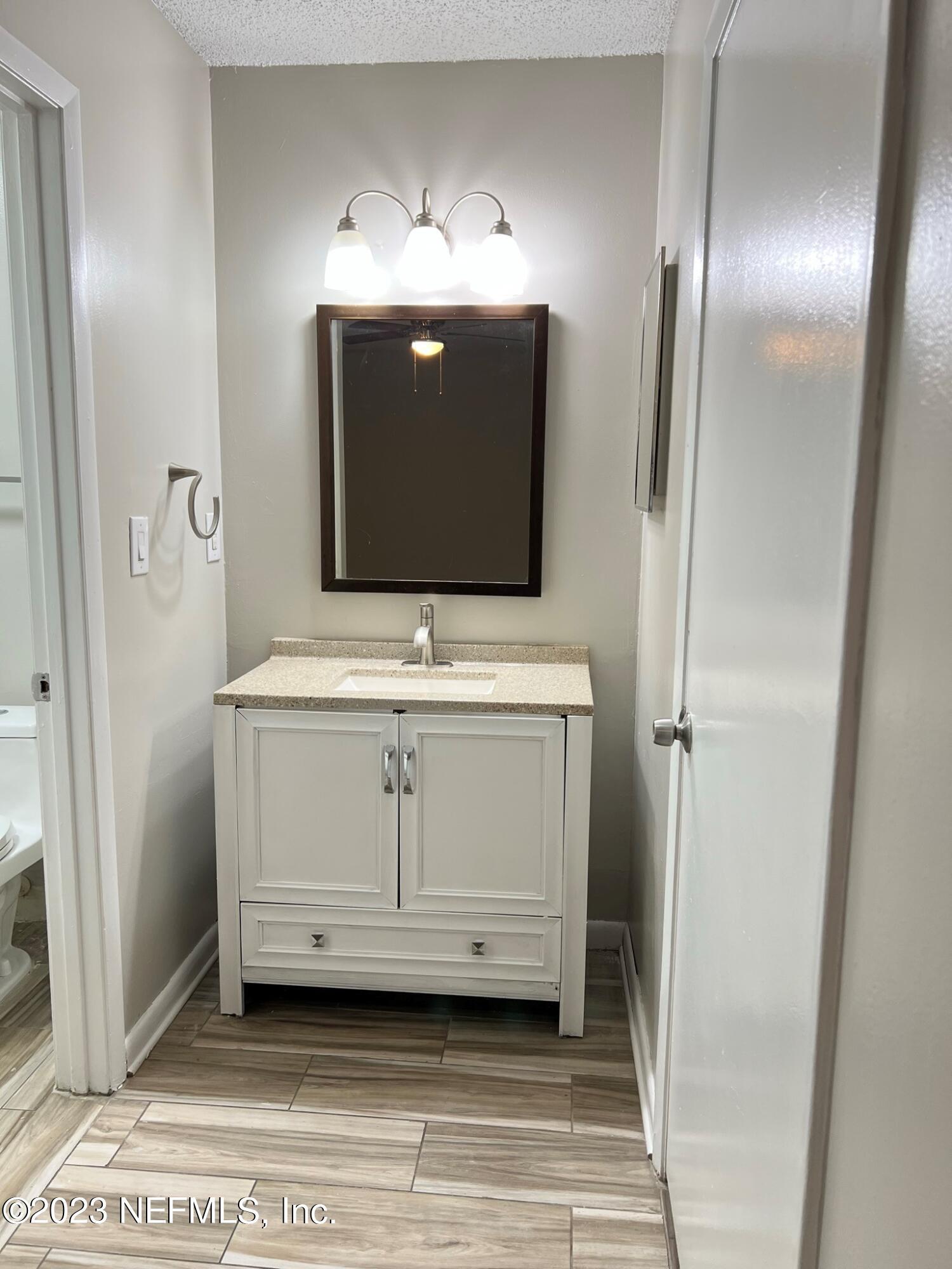 5404 101st Street, Unit 4 Jacksonville, FL 32210 - Photo 6 of 8 a bathroom with a sink a light fixture and a mirror