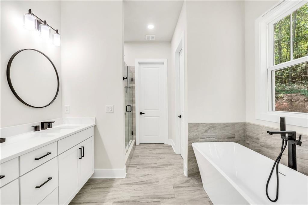 5567 Tyree Road Winston, GA 30187 - Photo 10 of 28 a bathroom with a double vanity sink a mirror a bathtub and shower