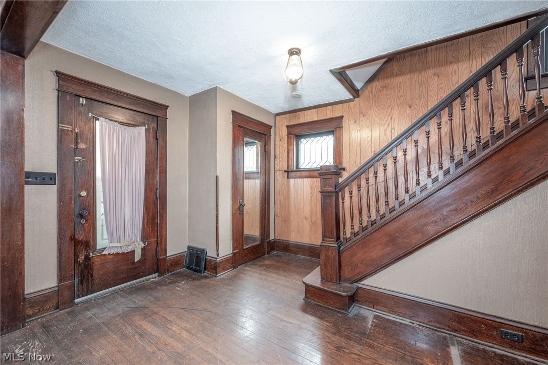 267 West Riddle Avenue Ravenna, OH 44266 - Photo 3 of 47 Hardwood flooring, wood paneling, dark wood-finish staircase with balusters, and a decorative window