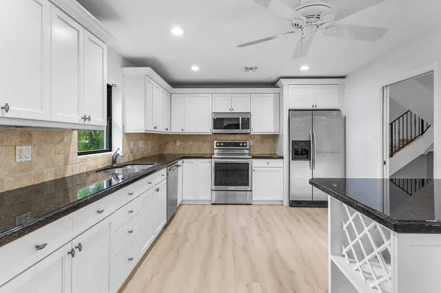 a kitchen with granite countertop white cabinets and white appliances