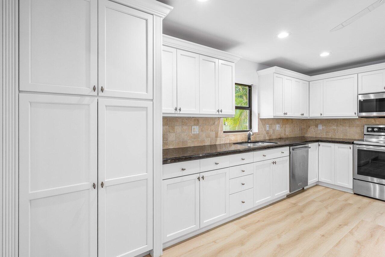 5109 North Ocean Boulevard, Unit H Ocean Ridge, FL 33435 - Photo 20 of 45 a kitchen with granite countertop white cabinets and white appliances