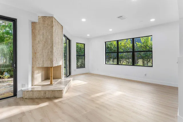 an empty room with large windows and a fireplace