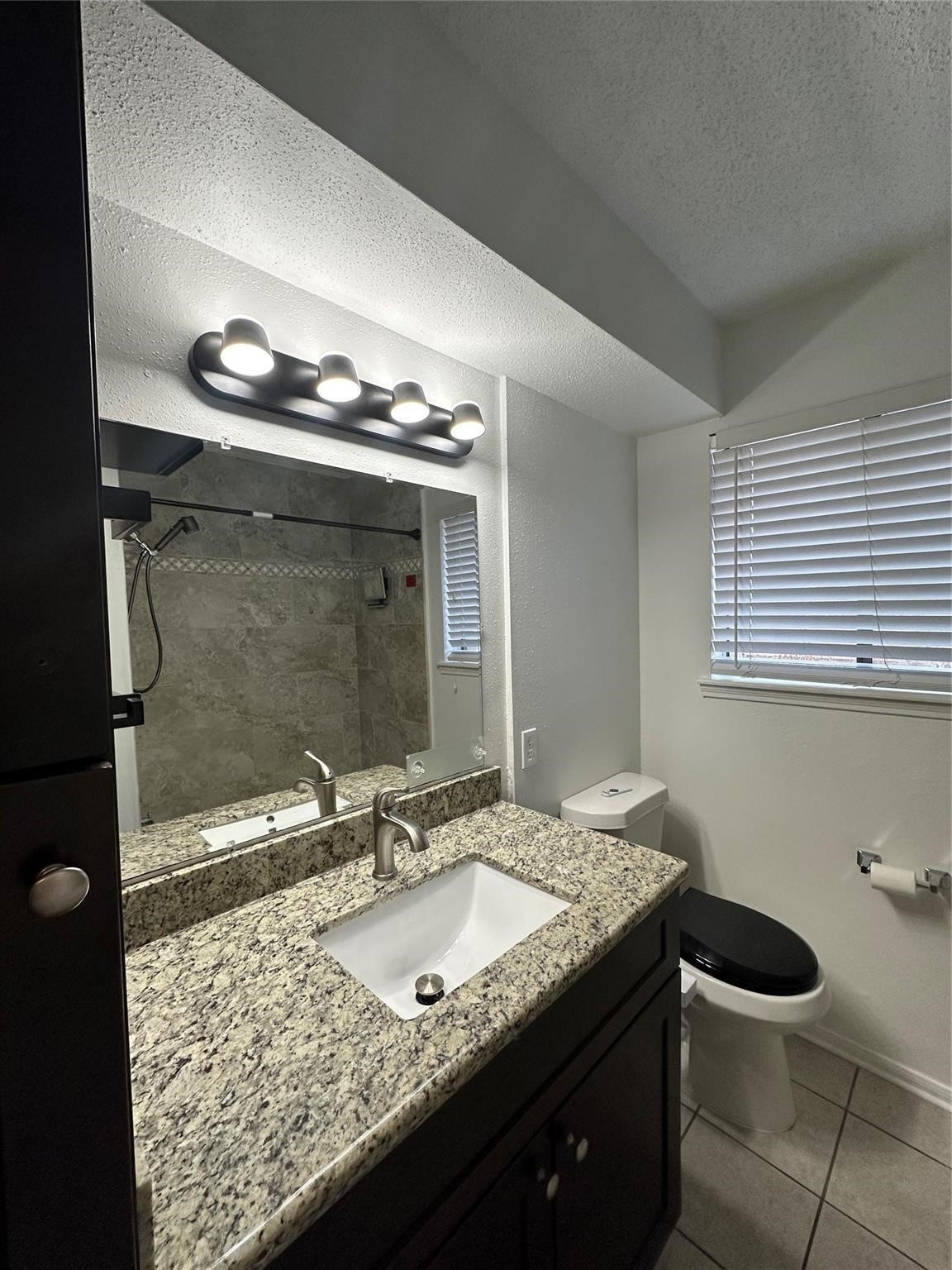 1410 Blalock Road, Unit 9 Houston, TX 77055 - Photo 13 of 18 a bathroom with a granite countertop sink a toilet and a mirror