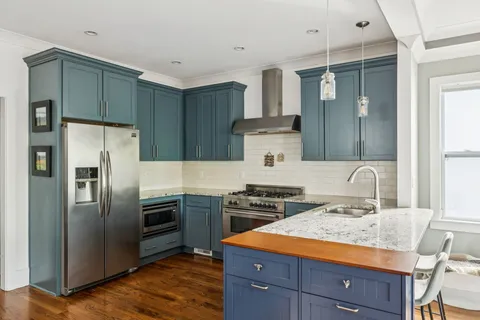 a kitchen with stainless steel appliances a dining table chairs and refrigerator