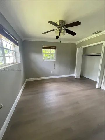 an empty room with windows and fan