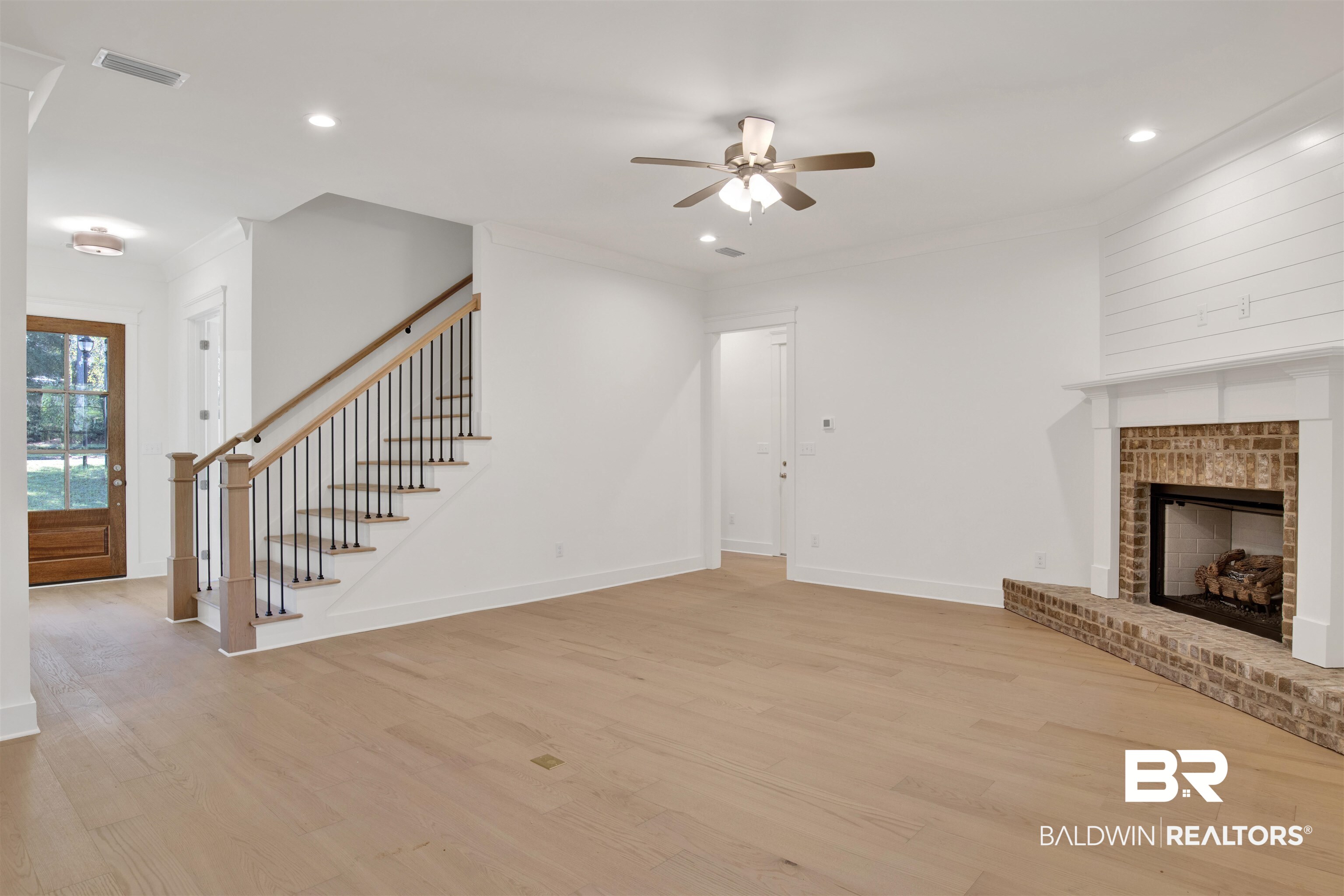 5 Long Leaf Circle Fairhope, AL 36532 - Photo 7 of 44 Unfurnished living room with light wood-type flooring, a brick fireplace, ceiling fan, and ornamental molding