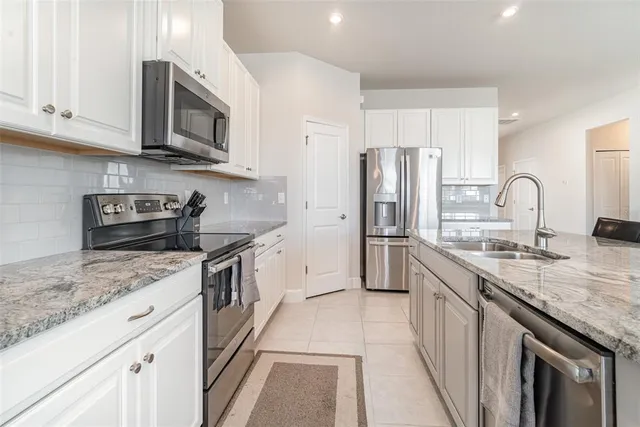 a kitchen with stainless steel appliances granite countertop a sink stove microwave and refrigerator