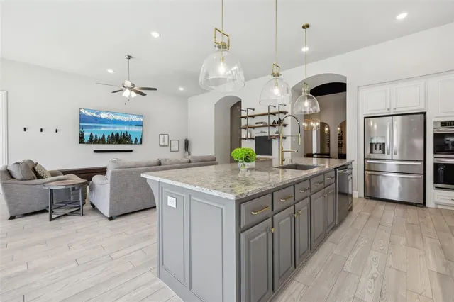 a kitchen with stainless steel appliances kitchen island granite countertop a refrigerator a stove a microwave oven a dining table and chairs with wooden floor