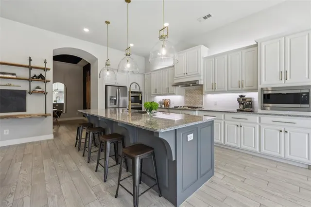 a kitchen with granite countertop a table chairs stove a sink dishwasher and cabinets with wooden floor