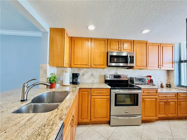 a kitchen with stainless steel appliances granite countertop a refrigerator a stove and a sink