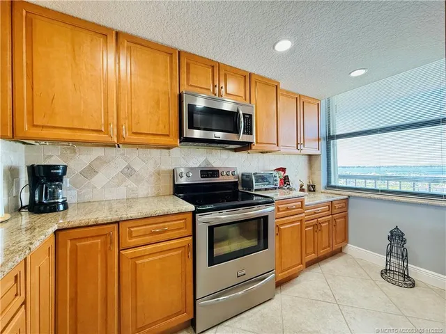 a kitchen with stainless steel appliances granite countertop a refrigerator a stove and a sink with cabinets