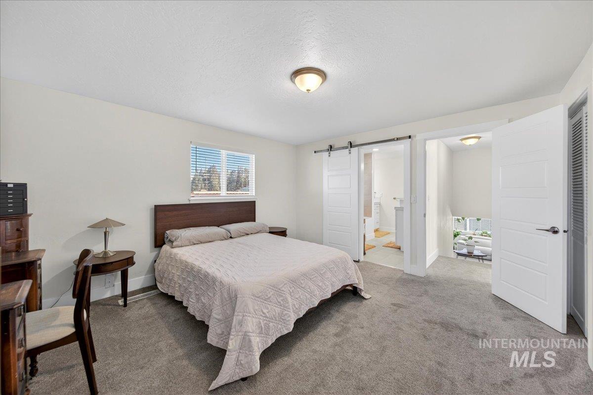 621 North Roosevelt Street Boise, ID 83706 - Photo 14 of 32 Bedroom featuring a barn door, carpet floors, a textured ceiling, and connected bathroom