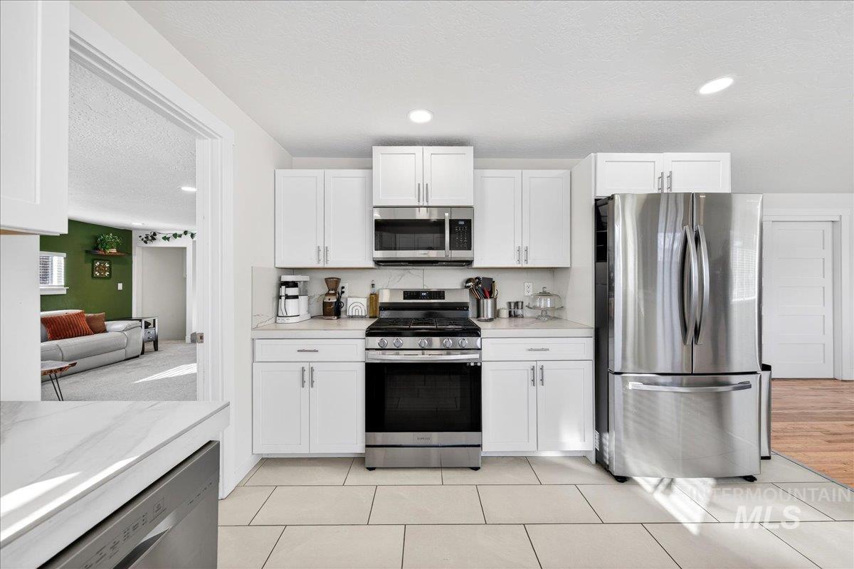 621 North Roosevelt Street Boise, ID 83706 - Photo 4 of 32 Kitchen with stainless steel appliances, white cabinets, a textured ceiling, light tile patterned floors, and recessed lighting