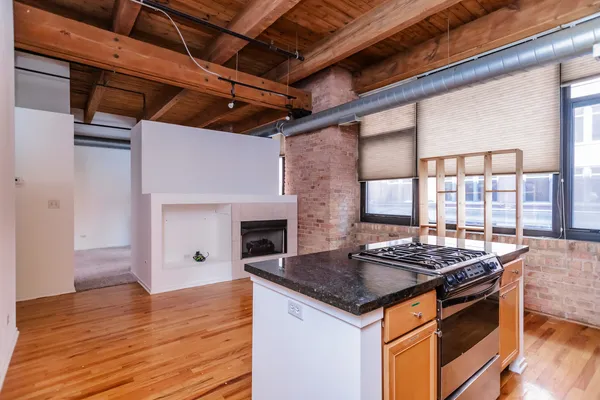 a kitchen view of a kitchen island wooden floors granite counter tops and a stove