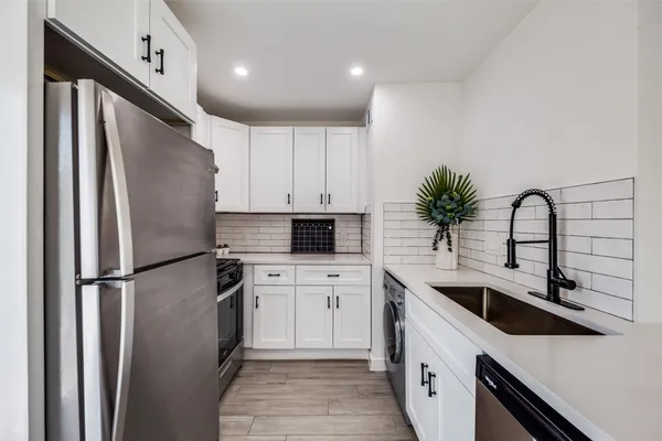 a kitchen with a refrigerator sink and white cabinets