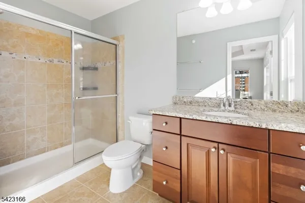 a bathroom with a granite countertop sink toilet mirror and bathtub