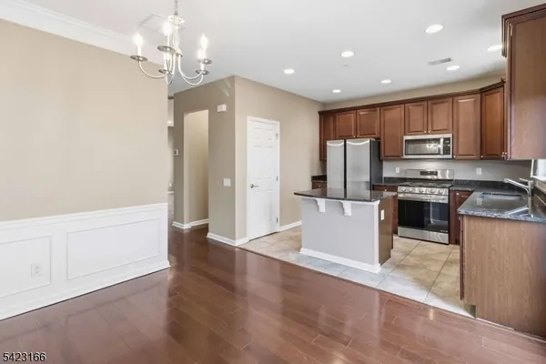 a kitchen with stainless steel appliances granite countertop a refrigerator a stove a sink and a oven with wooden floor