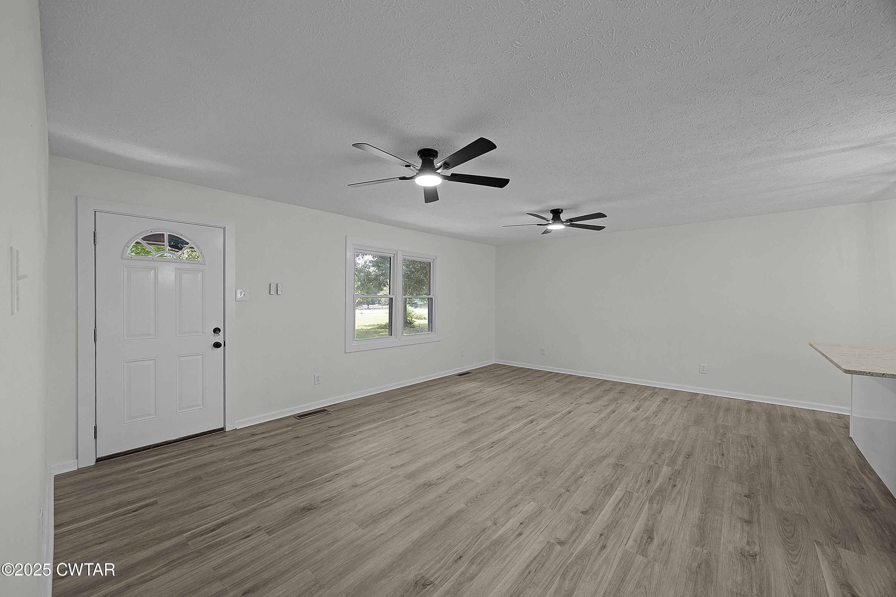 649 Spring Creek Law Road Jackson, TN 38305 - Photo 3 of 20 an empty room with wooden floor chandelier fan and windows