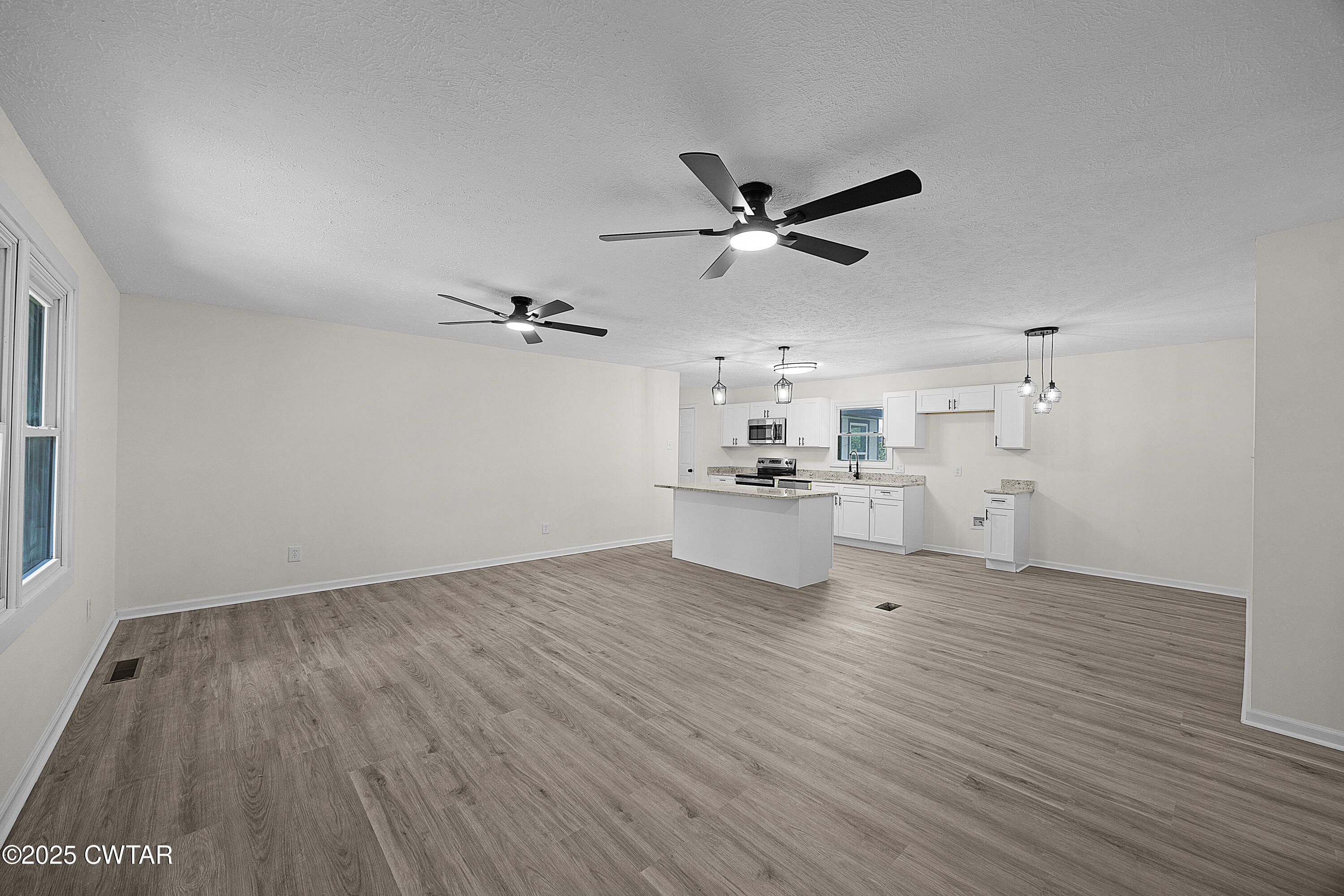 649 Spring Creek Law Road Jackson, TN 38305 - Photo 5 of 20 a view of a big room with wooden floor a kitchen space and appliances