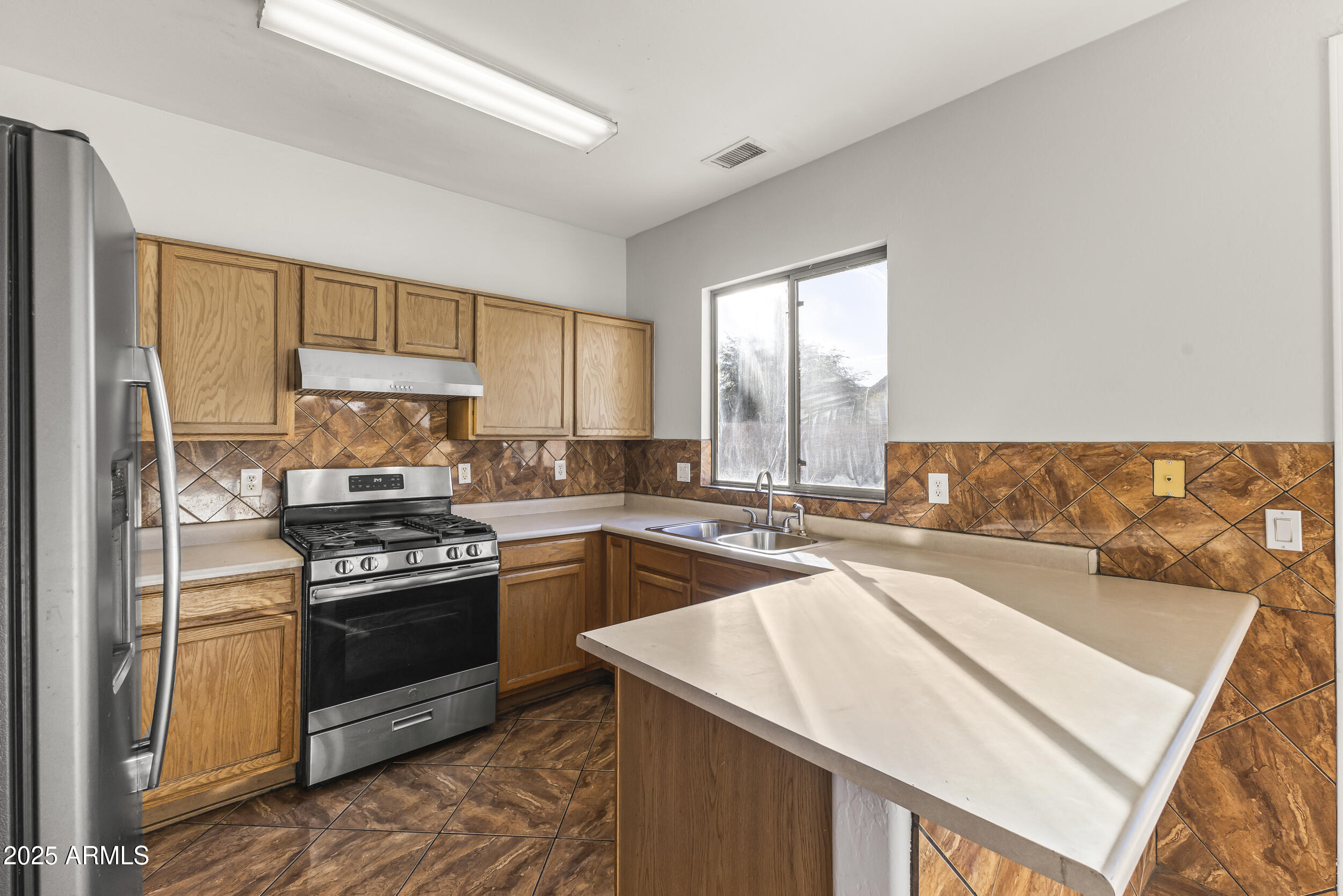 11185 West Coronado Road Avondale, AZ 85392 - Photo 26 of 46 a kitchen with stainless steel appliances granite countertop a stove a sink and a refrigerator