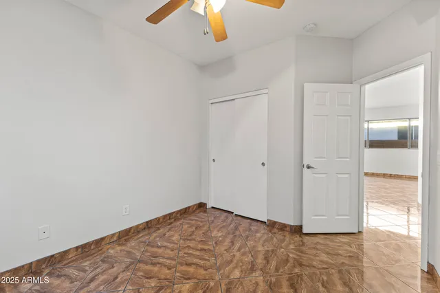 an empty room with chandelier fan and windows