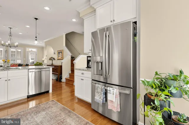 a kitchen with stainless steel appliances a refrigerator a sink cabinets and wooden floor