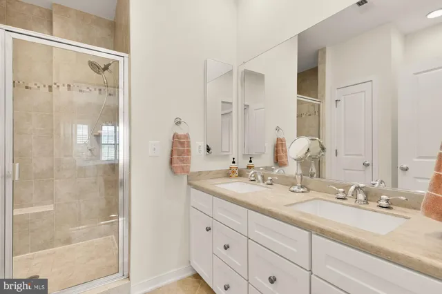 a bathroom with double vanity sinks and a shower