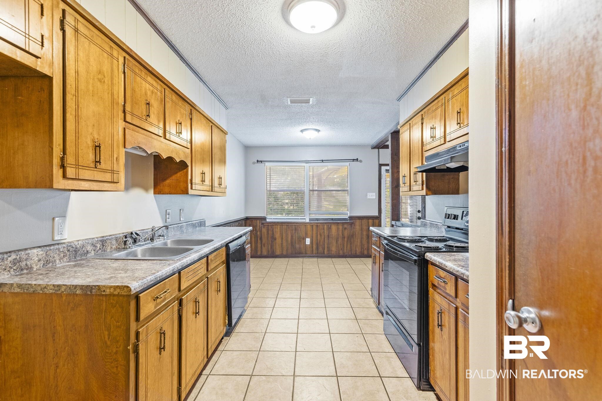 4151 Springdale Road Mobile, AL 36609 - Photo 13 of 21 Kitchen with light tile patterned floors, a textured ceiling, black appliances, wooden walls, and sink