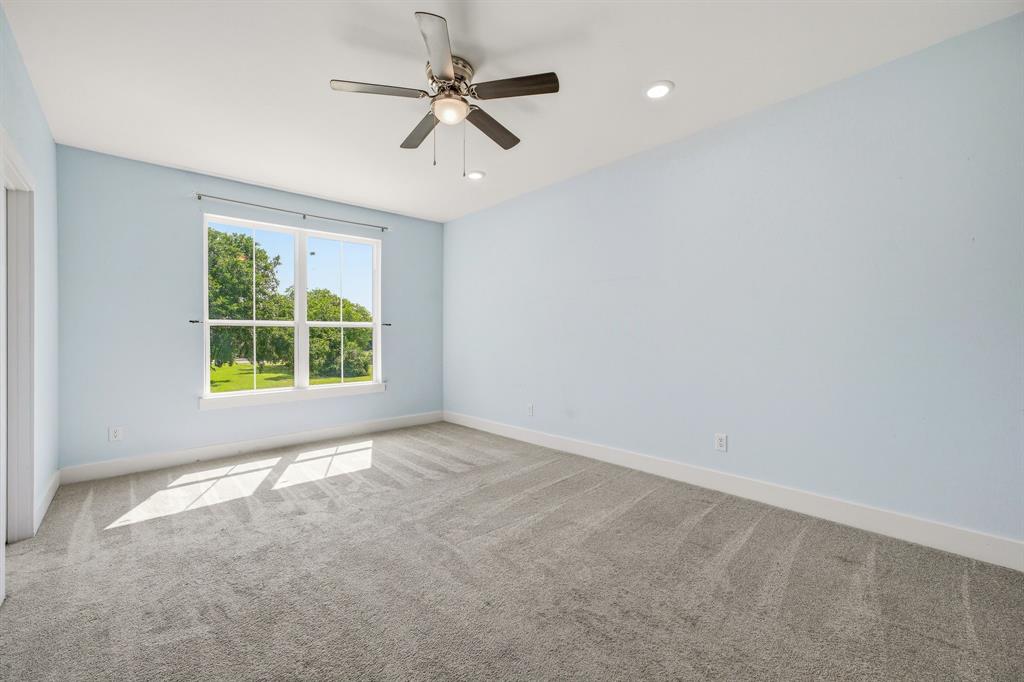 745 North Miller Avenue Stephenville, TX 76401 - Photo 16 of 31 Spacious room with a large multi-pane window, light-toned carpeting, a ceiling fan with integrated lighting, and recessed ceiling lights
