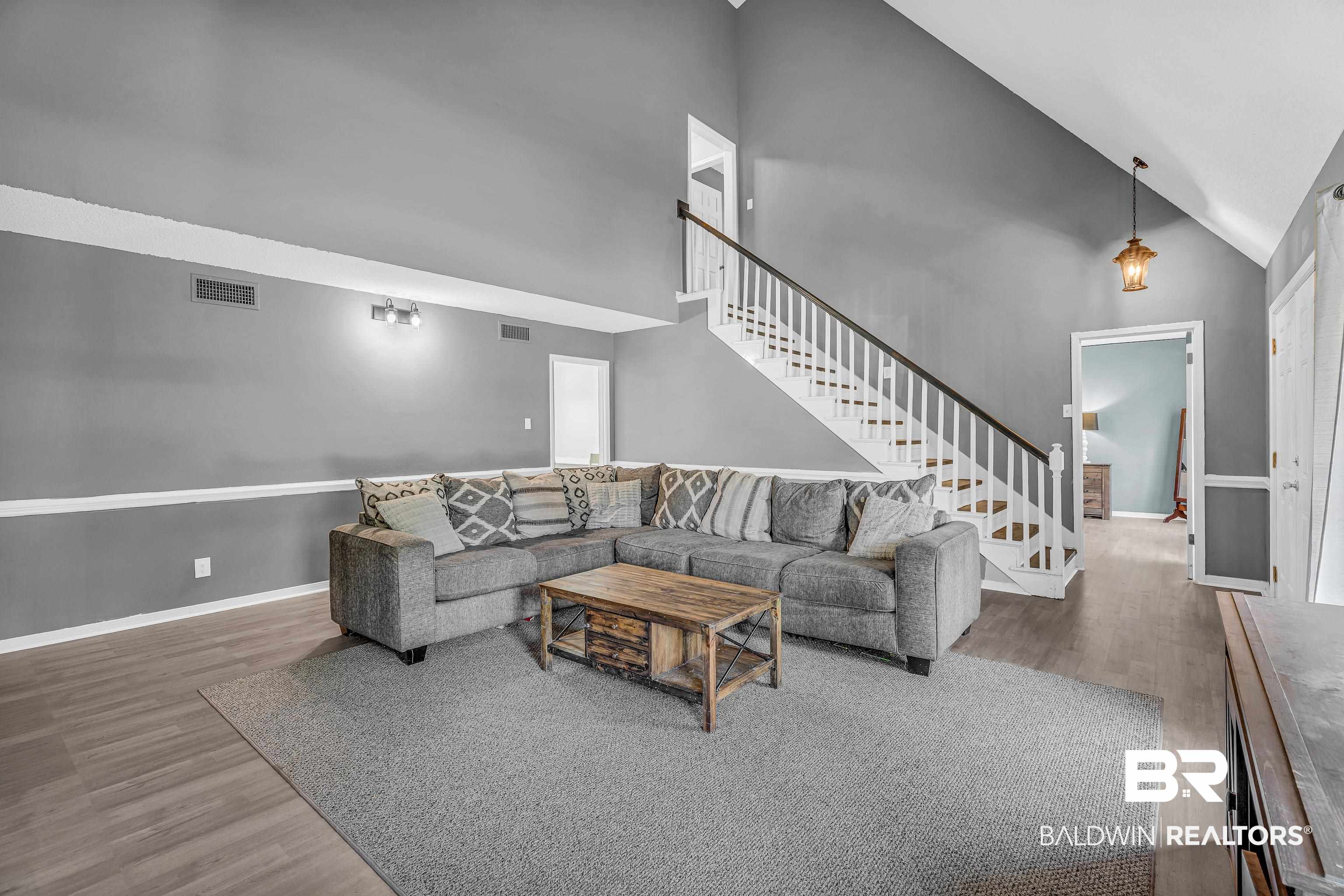 6135 Oak Cliff Drive Eight Mile, AL 36613 - Photo 6 of 30 Living room with high vaulted ceiling, wood finished floors, and stairway