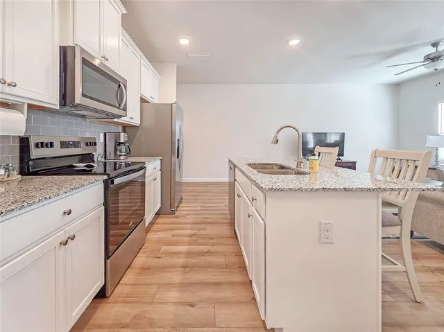 a kitchen with stainless steel appliances granite countertop a sink stove microwave and cabinets