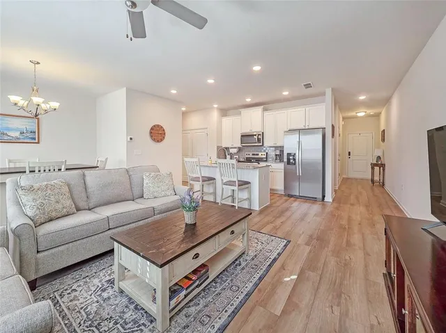 a living room with stainless steel appliances furniture and a view of kitchen