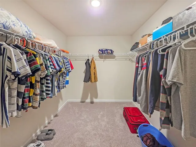 a view of walk in closet with clothes and shoes