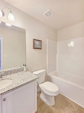 a bathroom with a granite countertop sink a toilet and shower