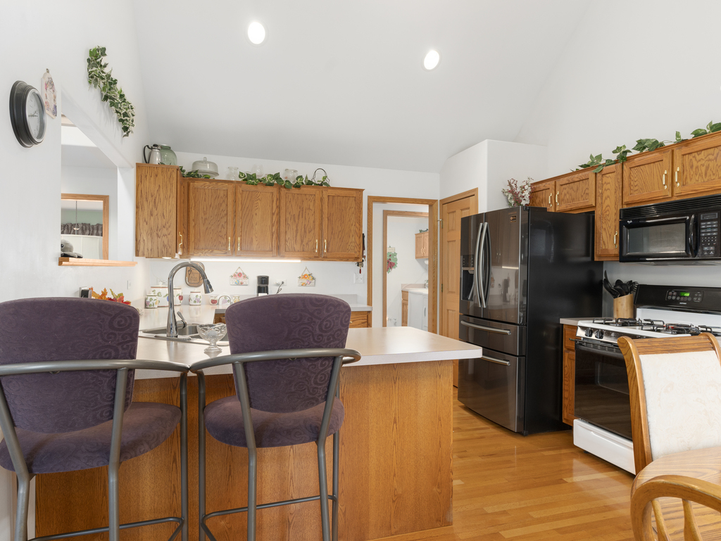 704 Clifford Drive Minooka, IL 60447 - Photo 5 of 25 a large kitchen with stainless steel appliances granite countertop a stove a refrigerator a microwave a dining table and chairs