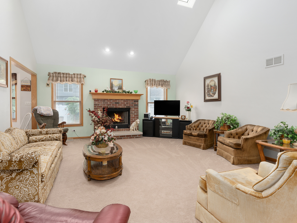 704 Clifford Drive Minooka, IL 60447 - Photo 10 of 25 a living room with furniture a flat screen tv and a fireplace