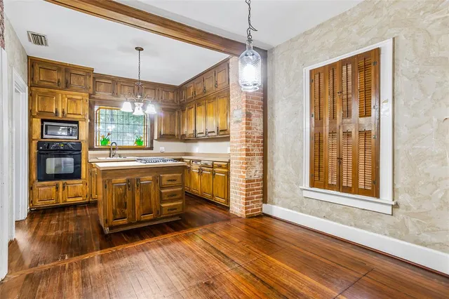 a kitchen with stainless steel appliances a stove top oven a refrigerator and a dining table with wooden floor