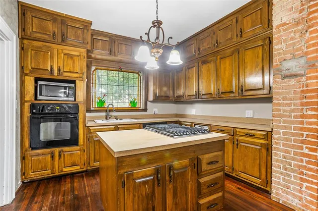 a kitchen with stainless steel appliances granite countertop a stove a sink dishwasher and a microwave oven with wooden floor