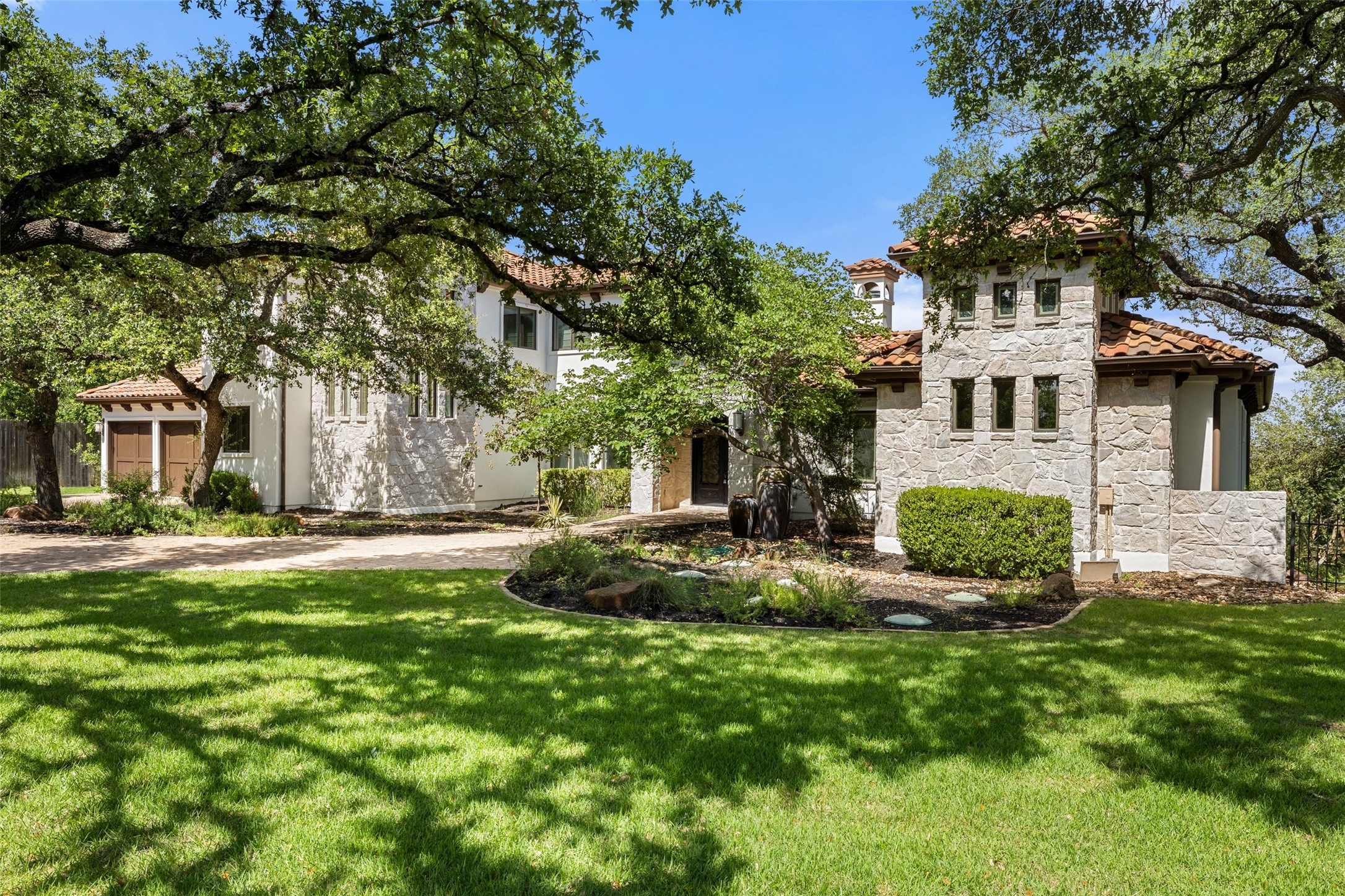 1414 The High Road Austin, TX 78746 - Photo 3 of 40 A stone and stucco facade with a terracotta roof creates an inviting, Mediterranean-inspired entrance.