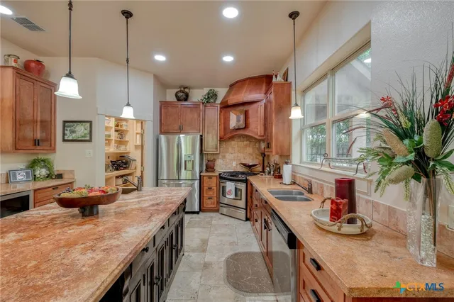a kitchen with stainless steel appliances granite countertop a sink a stove and a wooden floors