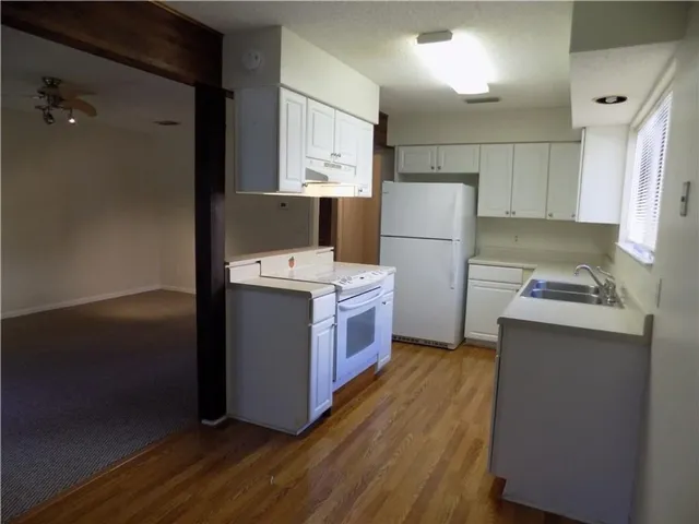 a kitchen with a refrigerator a sink and wooden floor
