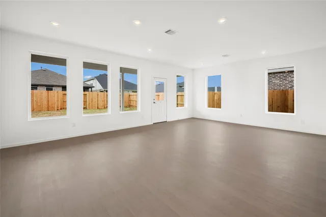a view of an empty room with a window and wooden floor