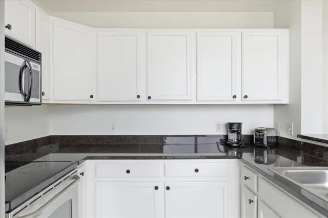 a kitchen with granite countertop white cabinets and a sink