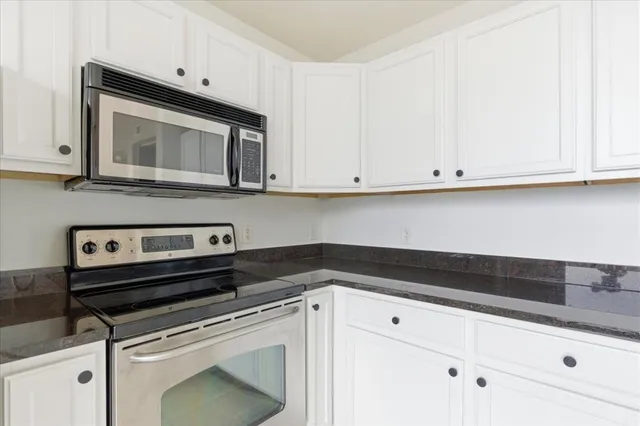 a kitchen with white cabinets and black appliances
