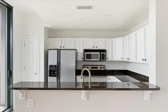 a kitchen with kitchen island a sink stainless steel appliances and white cabinets