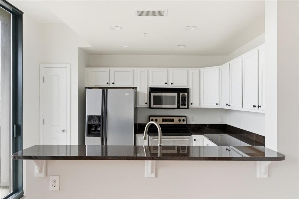 3040 Peachtree Road Northwest, Unit 805 Atlanta, GA 30305 - Photo 19 of 36 a kitchen with kitchen island a sink stainless steel appliances and white cabinets