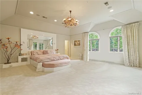 a spacious bedroom with a balcony a bed and a chandelier